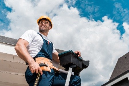 low angle view of happy repairman in helmet holdin 6Q47CSJ